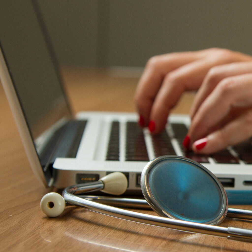 Main sur un clavier d'ordinateur avec en premier plan un stéthoscope.