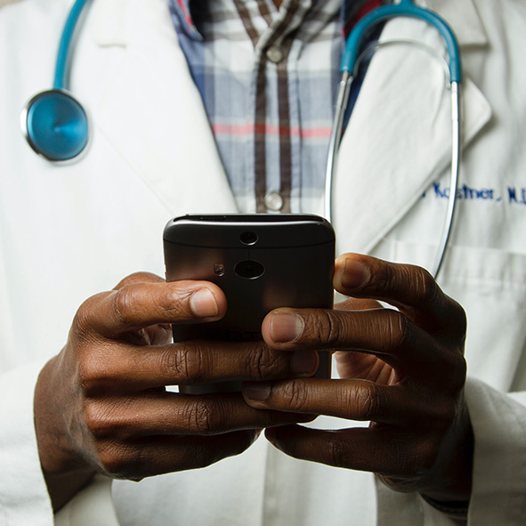 Photographie d'un docteur avec un stéthoscope autour du coup et un smartphone dans les mains